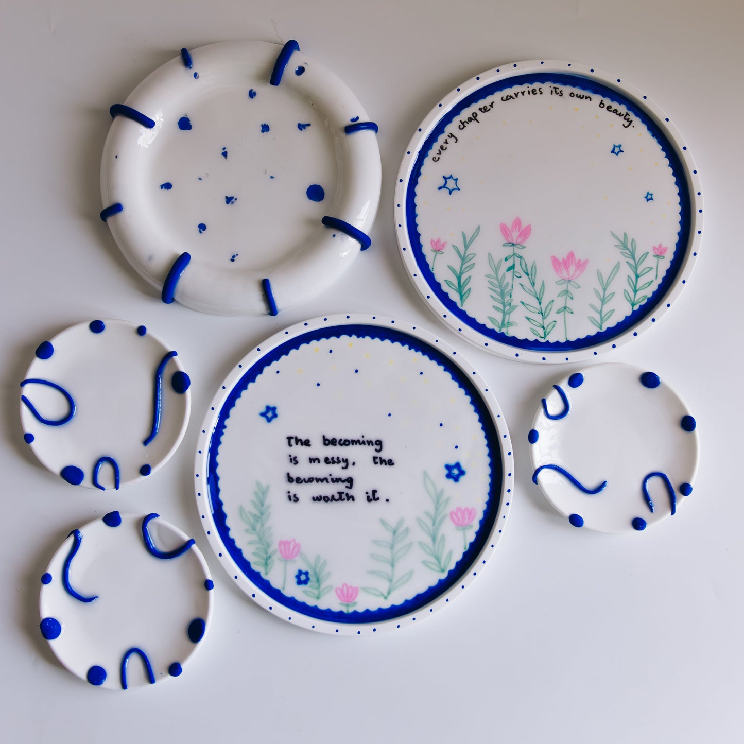 Set of decorative ceramic plates with blue and pink designs on a white background